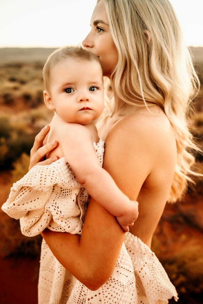 Family Photographer, a mother holds her baby girl outside in the wilderness