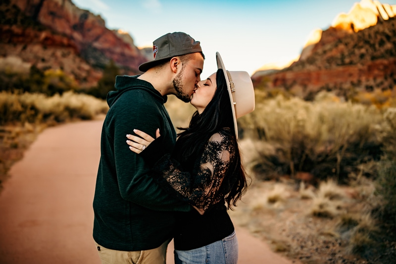 Vacation Photographer, man and woman kiss as they stand on the a path in the Utah wilderness