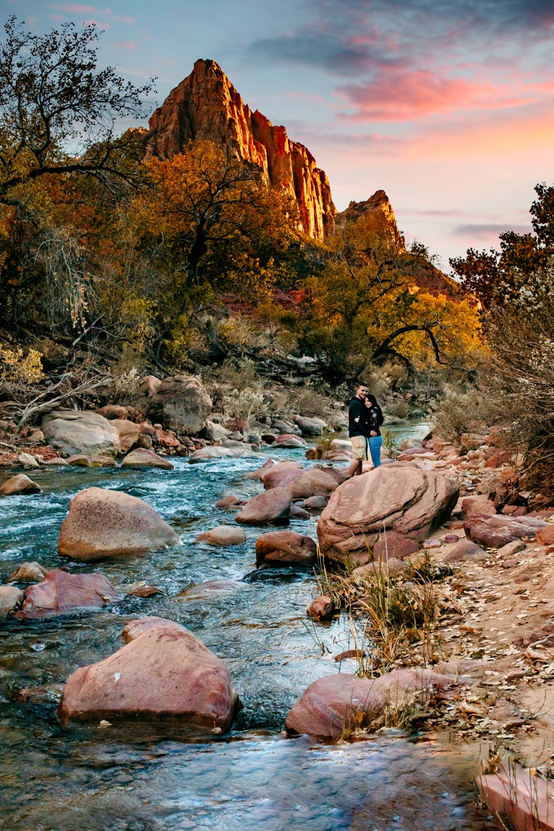 Vacation Photographer, a couple stand on large rocks near a river in the wilderness