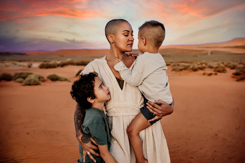 Motherhood Photographer, mother holds her two young sons in the desert at dusk