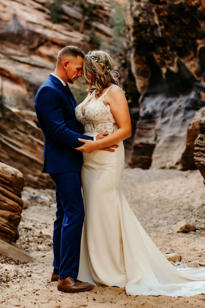 Elopement Photographer, newly eloped husband and wife stand dressed up beneath canyon walls