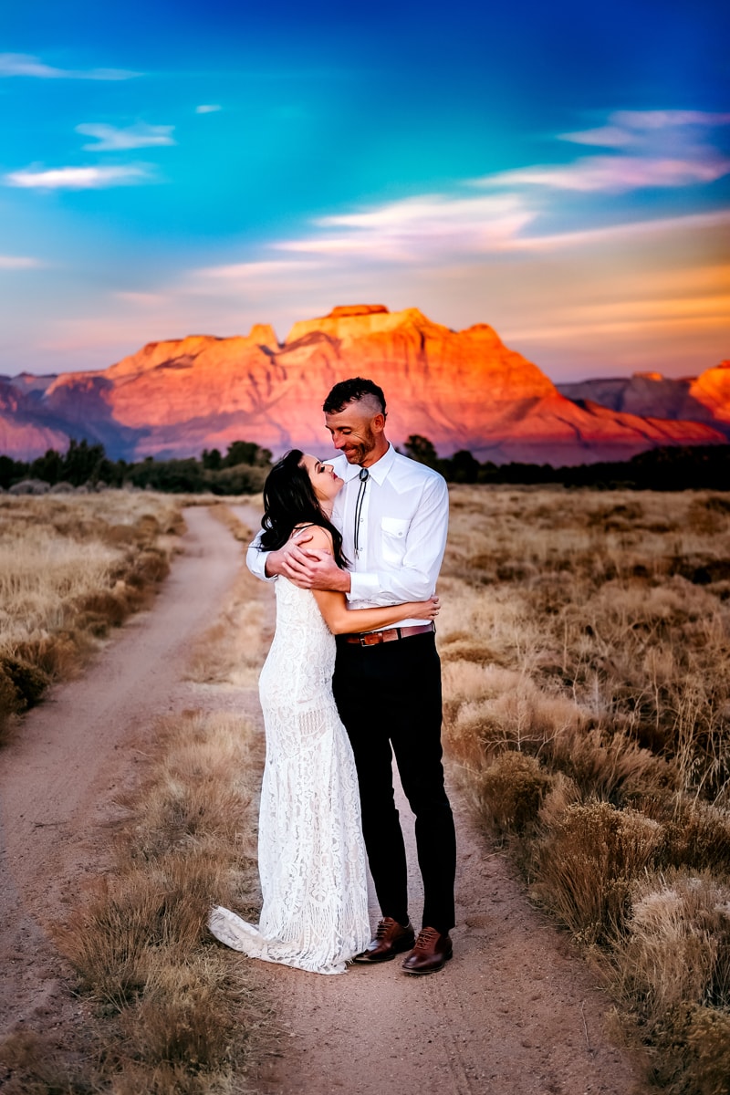 Elopement Photographer, newly married husband and wife embrace before utah wilderness at sunset
