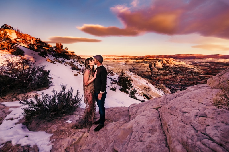 Elopement Photographer, man and woman kiss on snow covered canyon edge