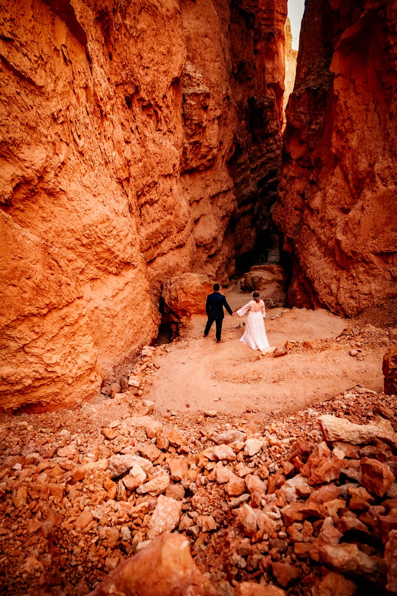 Elopement Photographer, in the distance a man and bride walk hand in hand in Bryce Canyon, Utah