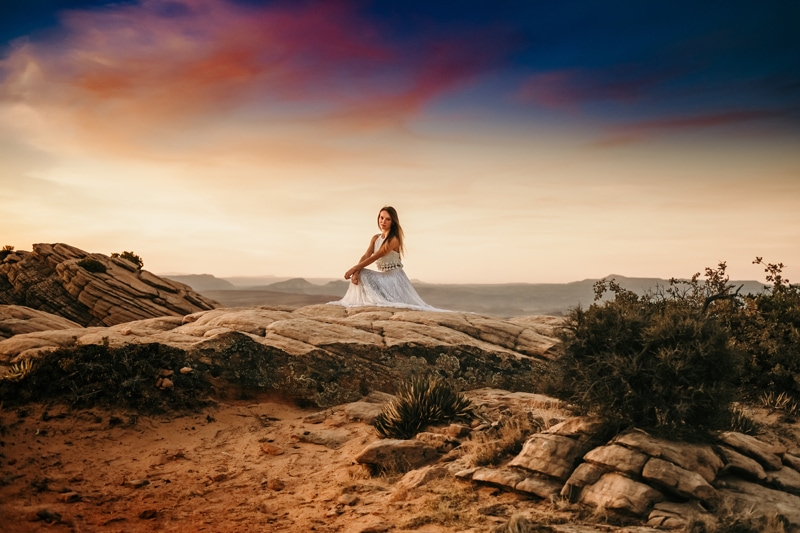 Elopement Photographer,  a bride sits on sand stone in Utah desert at sunset