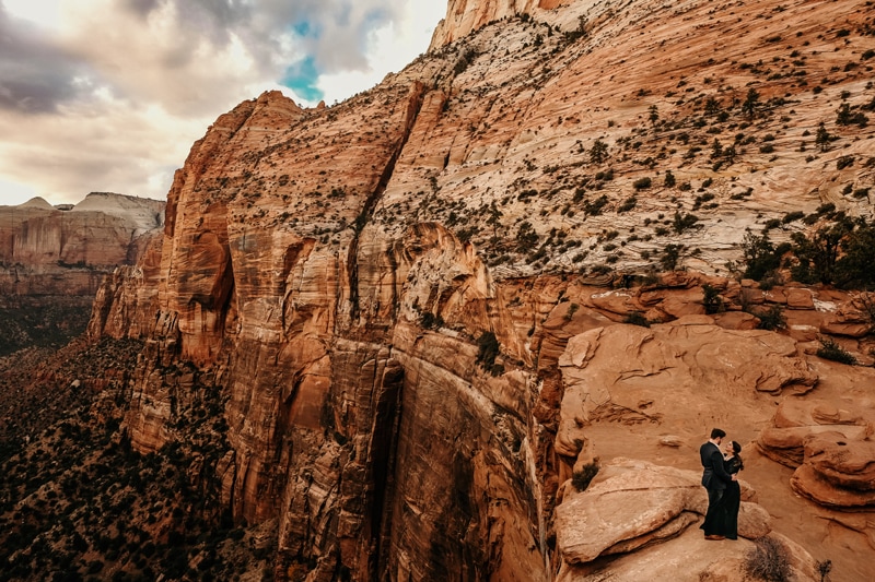 Elopement Photographer, a couple embrace as they stand on Utah Canyon wall