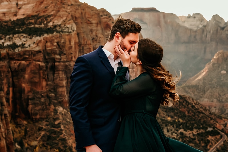 Vacation Photographer, a woman grabs her husbands face and kisses him in ZIon, they are all dressed up