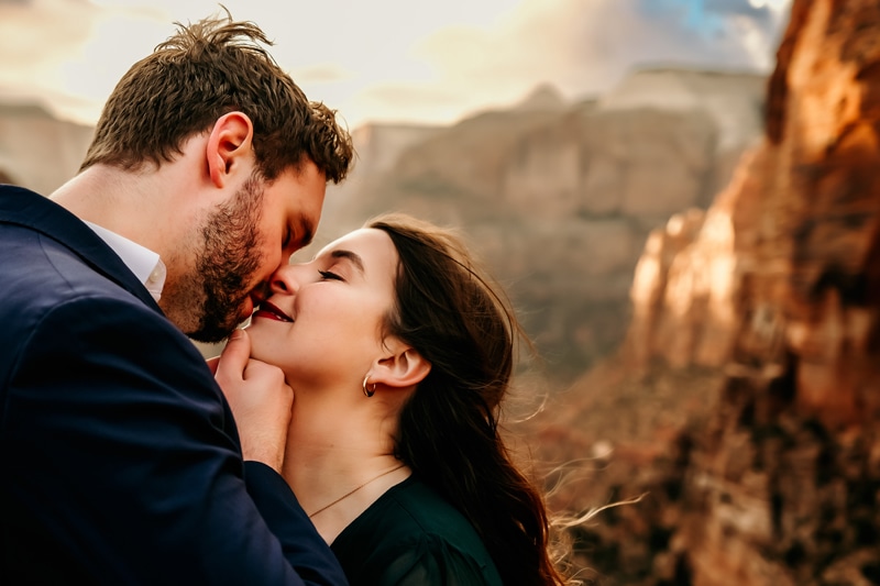 Vacation Photographer, a man and woman fondly share a kiss within Zion National Park
