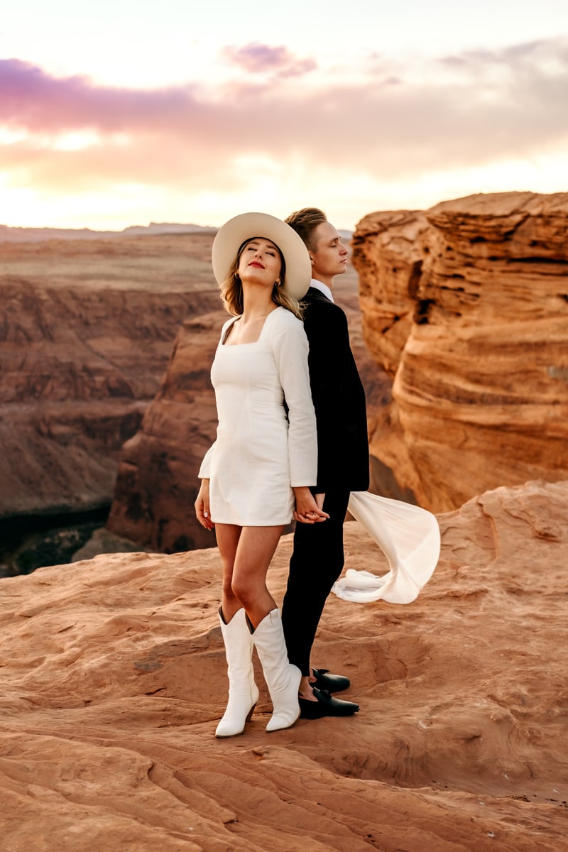 Elopement Photographer,  bride and groom stand back to back and stand atop canyon walls before a river