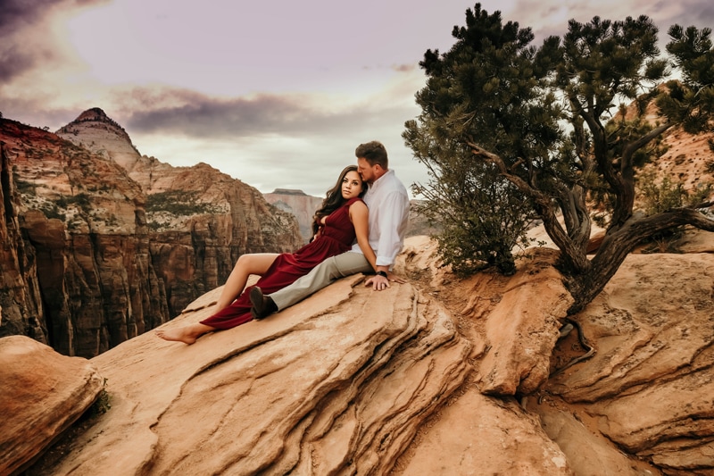 Vacation Photographer, man and woman recline into each other as they sit atop canyon walls in Zion