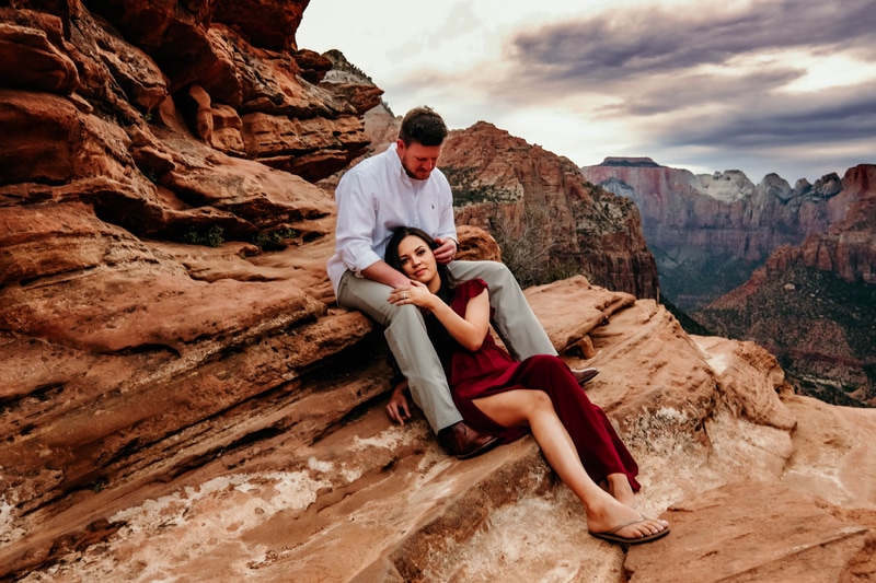 Elopement Photographer, a woman leans into her man as the sit near Canyon wall's edge