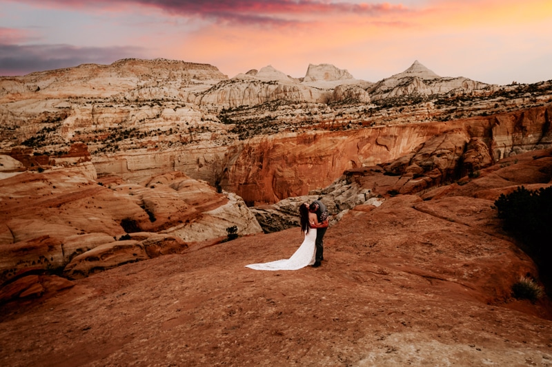 Elopement Photographer, groom kisses bride as they stand in Utah wild, she is in wedding dress