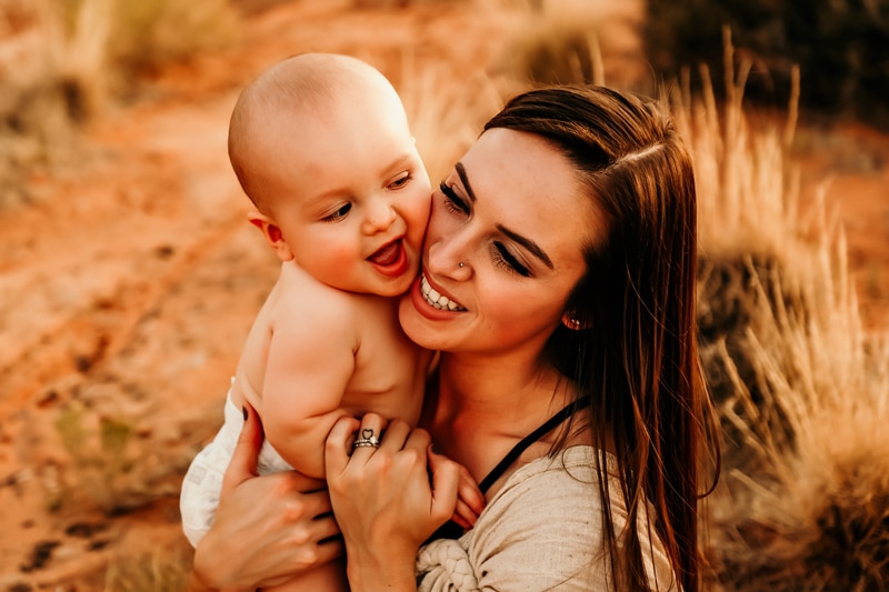 Motherhood Photographer,  mom and baby smiles as she holds him cheek to cheek, they are outdoors