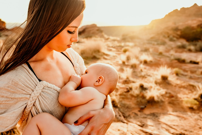 Motherhood Photographer, young mother admires her baby as she holds him on a walk in the desert